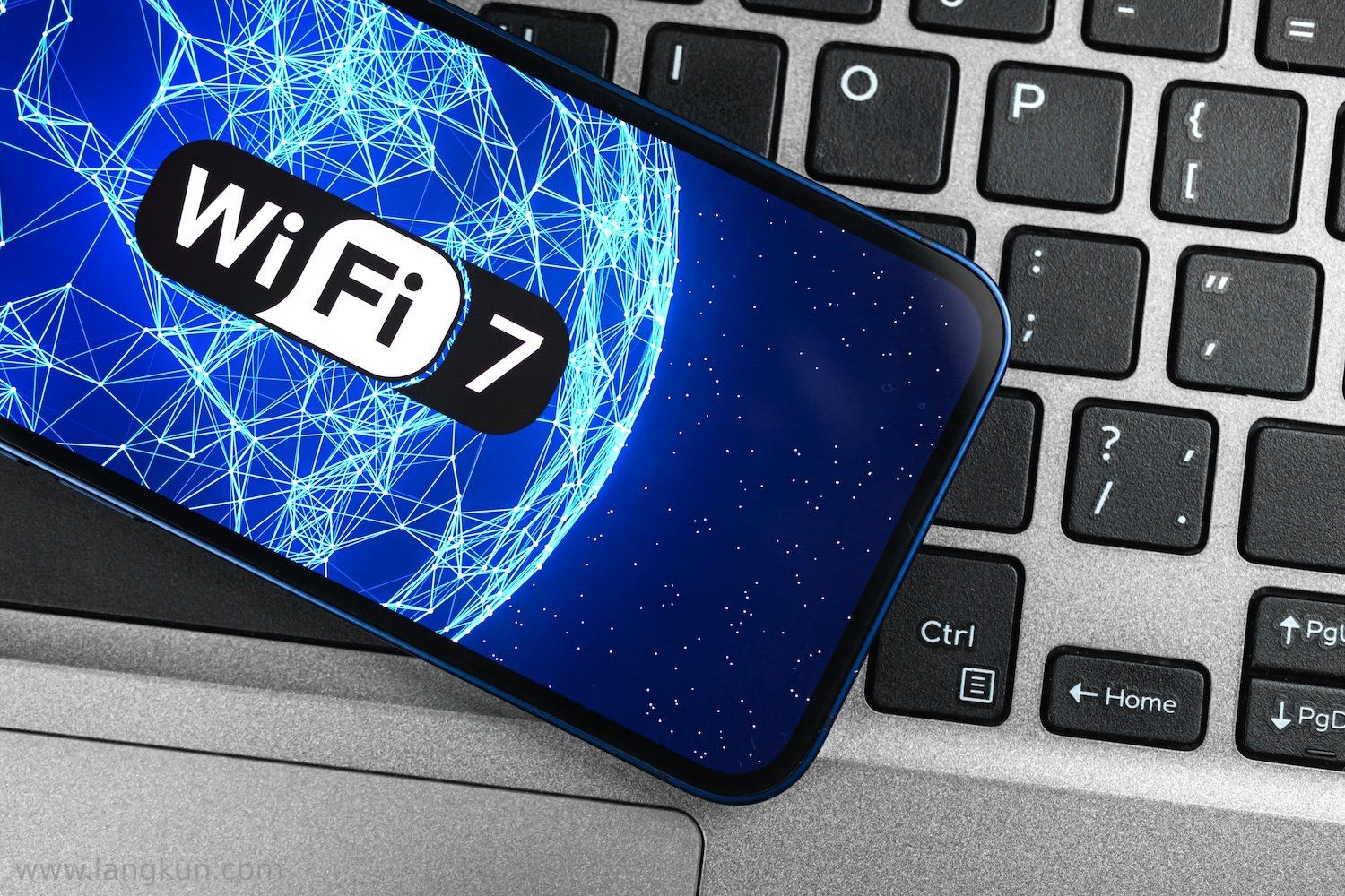 智能手机放在键盘上，显示着Wi-Fi 7的标志。